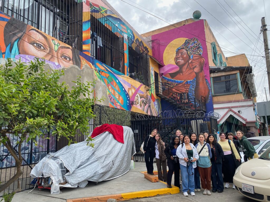 The 12 members of the first cohort of Crossing Borders: Human Rights, Journalism, and The Law pose for a photo outside Espacio Migrante in Tijuana, Mexico.