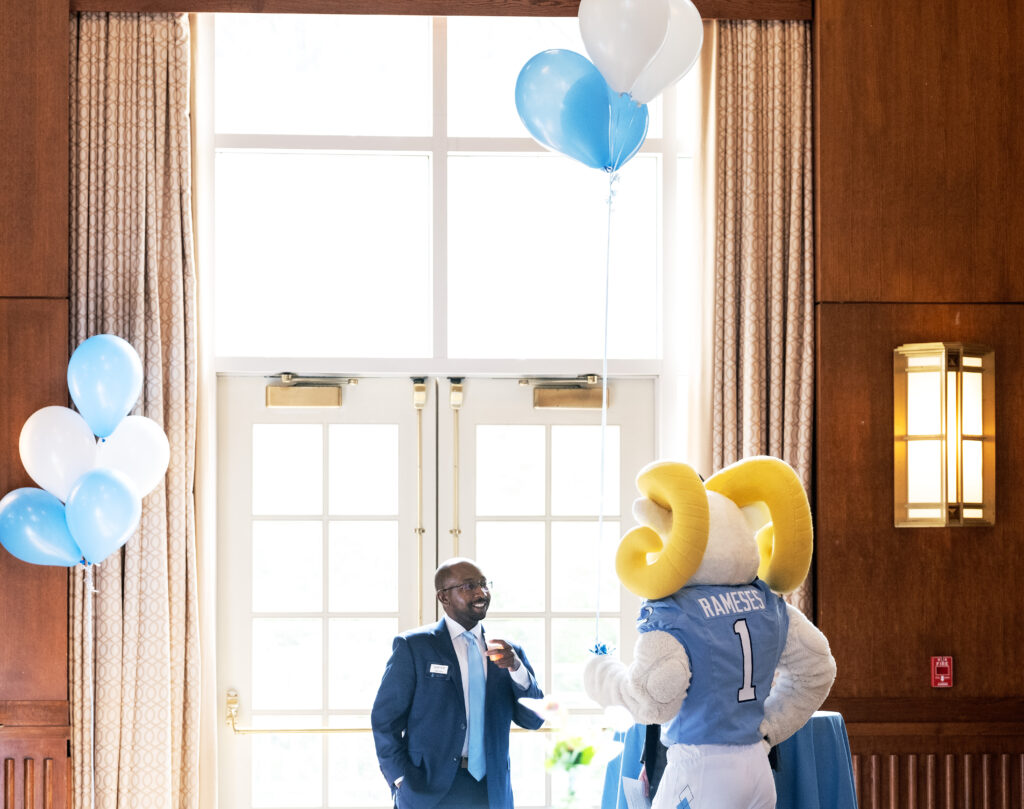 a man chats with the UNC Rameses mascot.