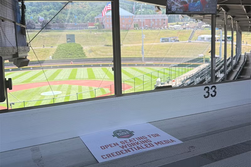 a view from a press box at a baseball stadium. A piece of paper reads "Open seating for working credentialed media"