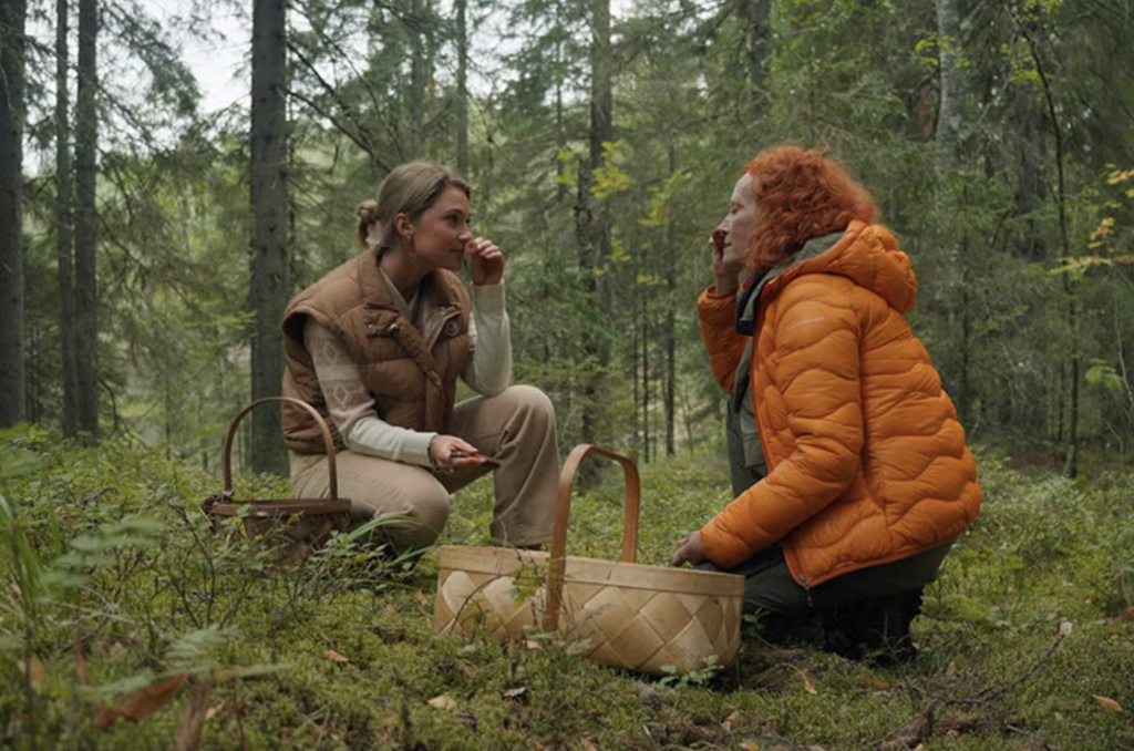 two women squat in the middle of a forest