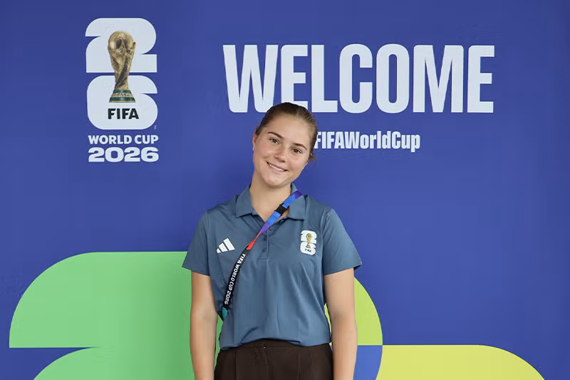 Mclaughlin stands in front of FIFA welcome sign.