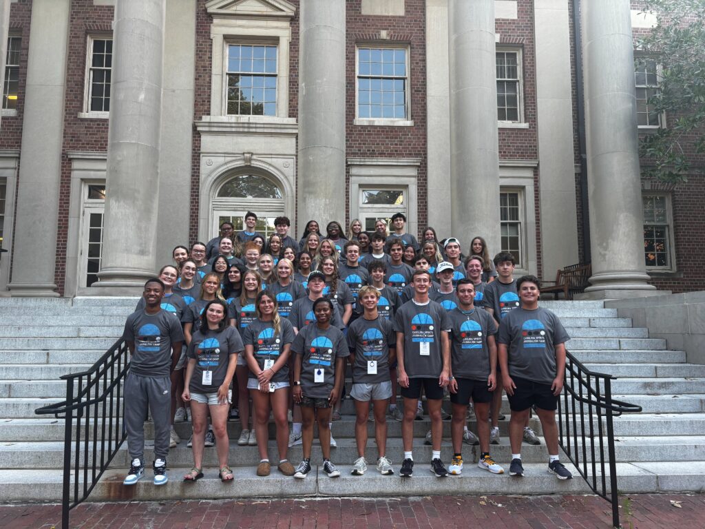 Participants wearing the same camp t-shirt stand on the steps of Carroll Hall.