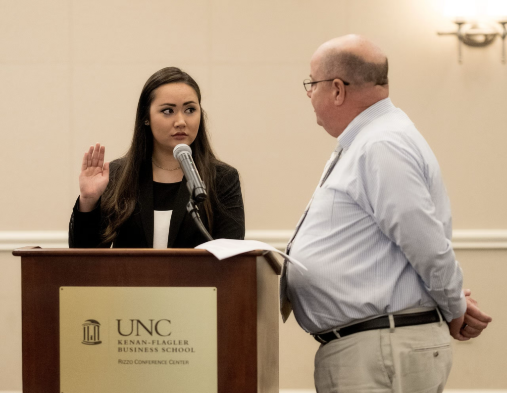 Elizabeth Adkins raises her right hand behind a podium.